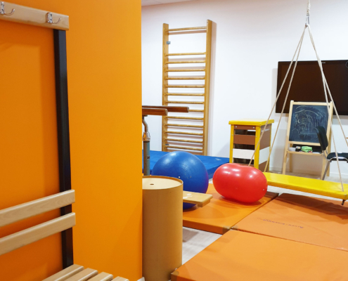 Salle de rééducation avec ballon, espaliers et balançoire pour séances de renforcement et prévention des incapacités